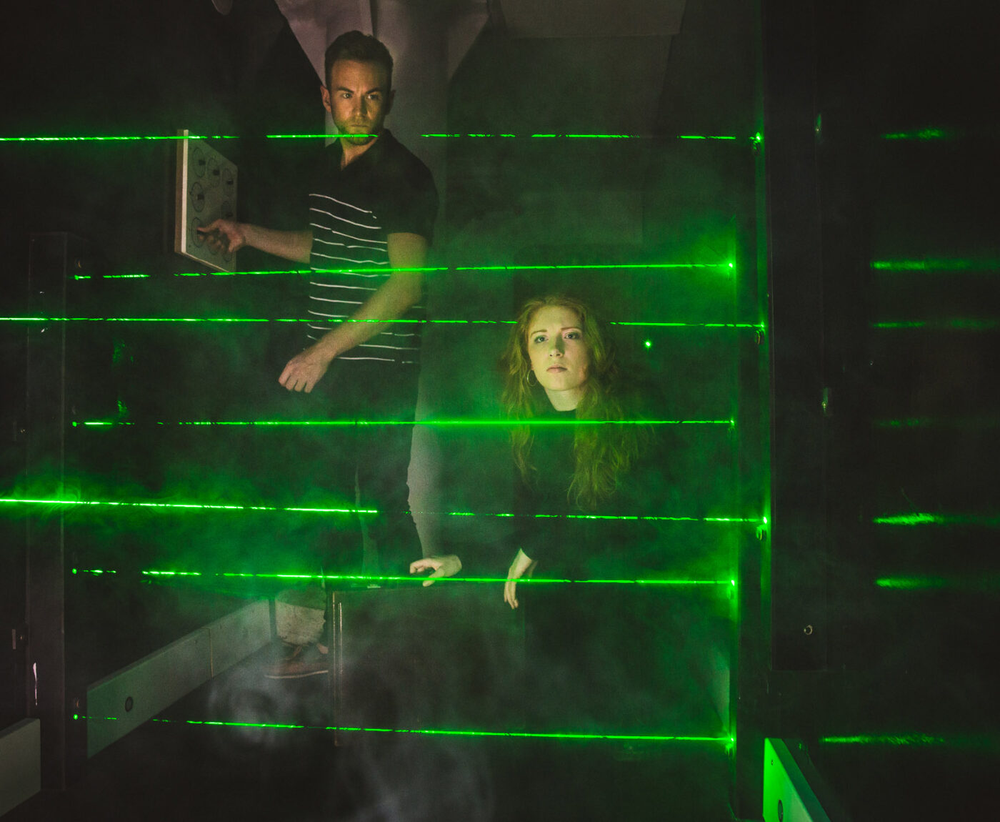 Man and woman trying to navigate laser security grid