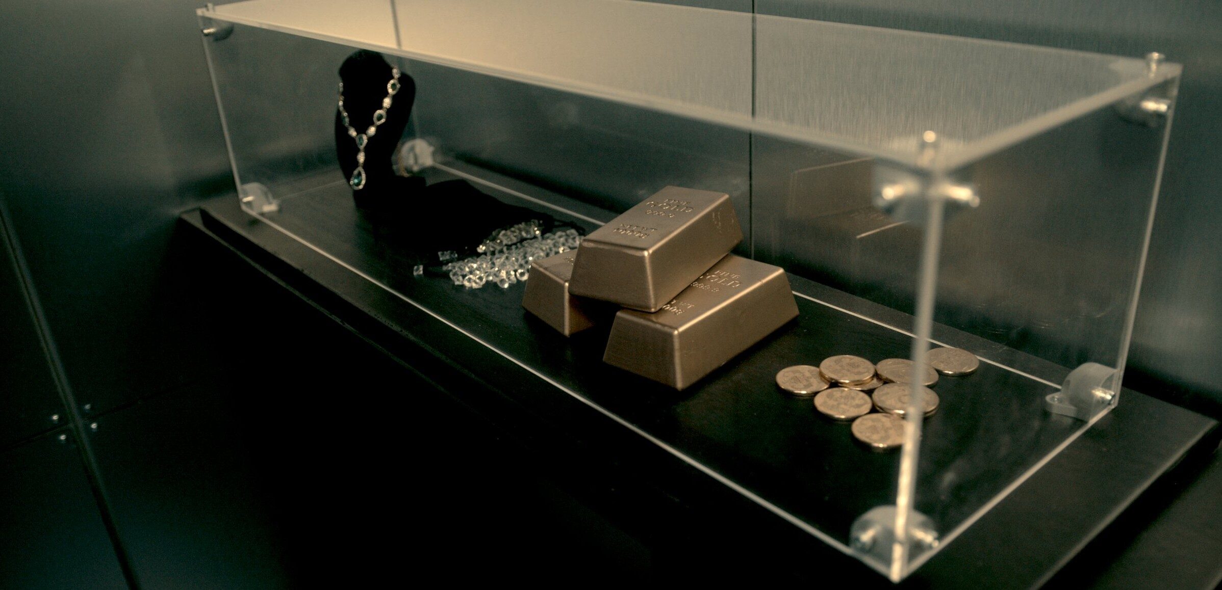 Gold bars and jewels within a glass case. Enigma Quests Escape Room The Billion Pound Heist